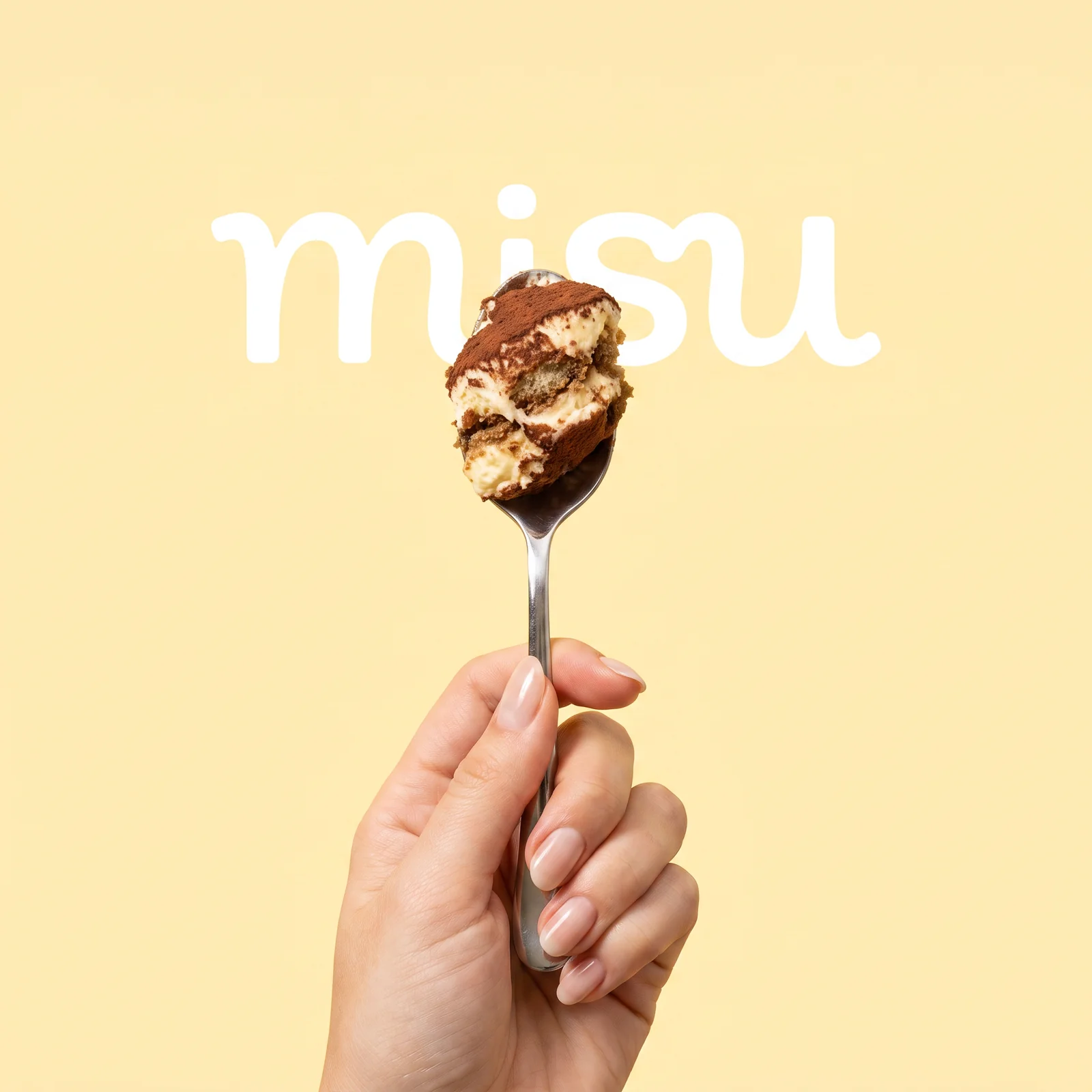 A hand holds a spoonful of tiramisu beneath the misu wordmark against a pale yellow background.